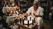 Traditional spiritual practitioner performing a candle ritual at a shrine, representing traditional cleansing practices and spiritual protection.